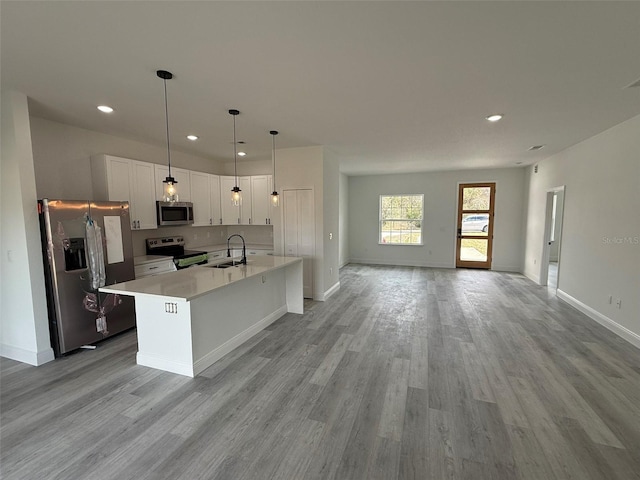 kitchen featuring stainless steel appliances, a sink, white cabinetry, light countertops, and light wood-type flooring