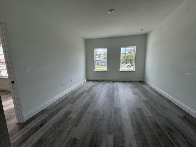 unfurnished room featuring baseboards, dark wood finished floors, and a textured ceiling