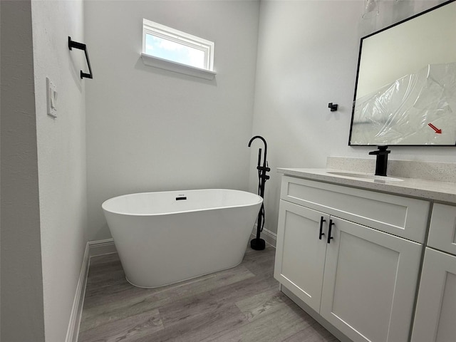 full bath with a freestanding tub, baseboards, wood finished floors, and vanity