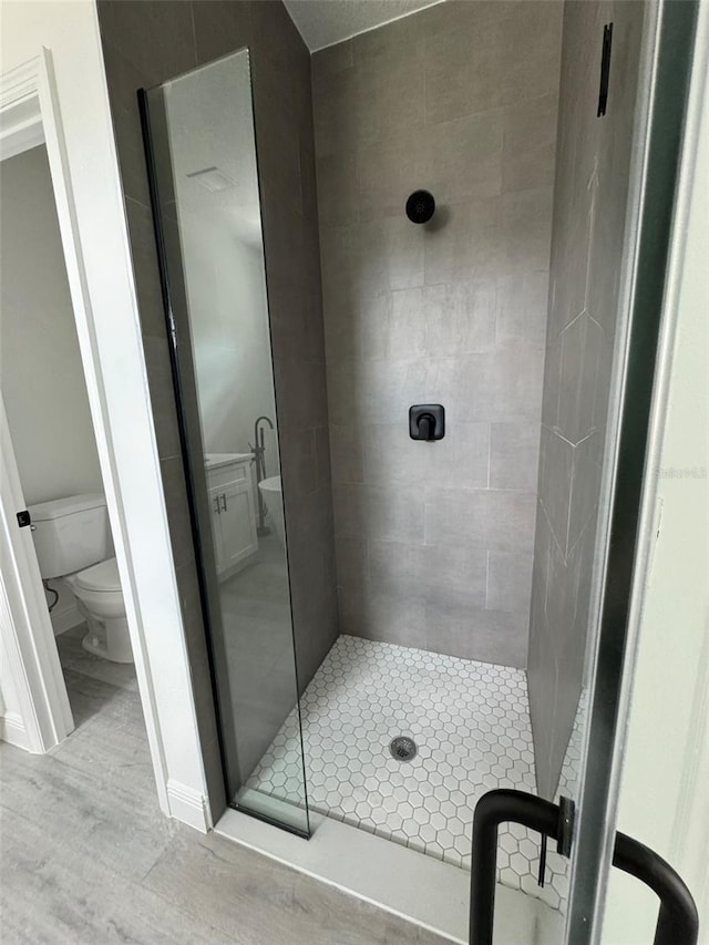 full bath with toilet, a stall shower, and wood finished floors