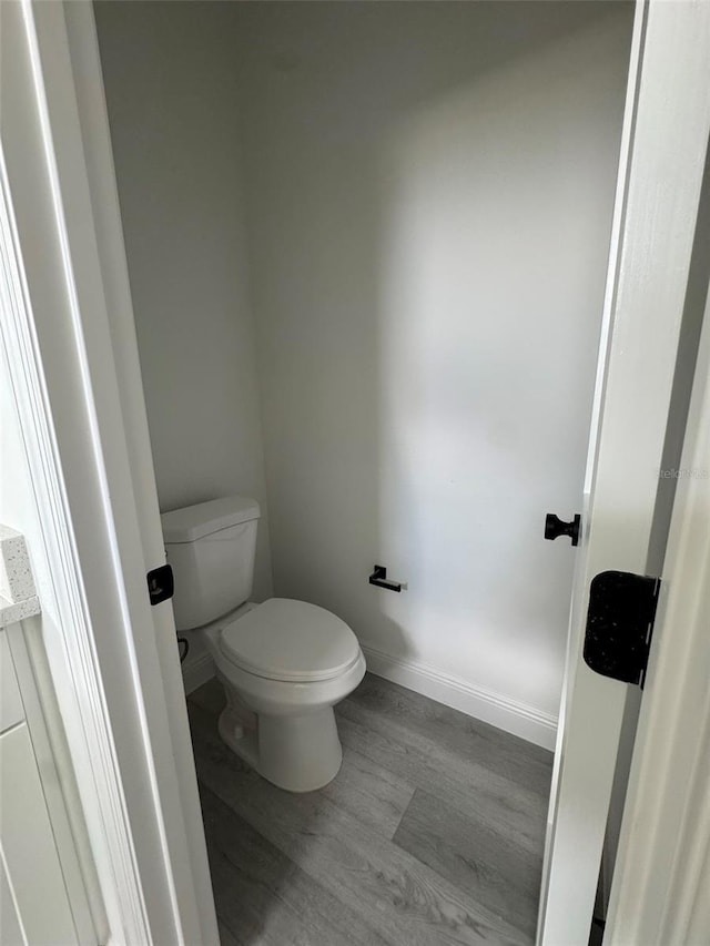 bathroom featuring toilet, baseboards, and wood finished floors