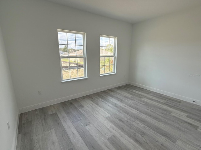 spare room with baseboards and wood finished floors