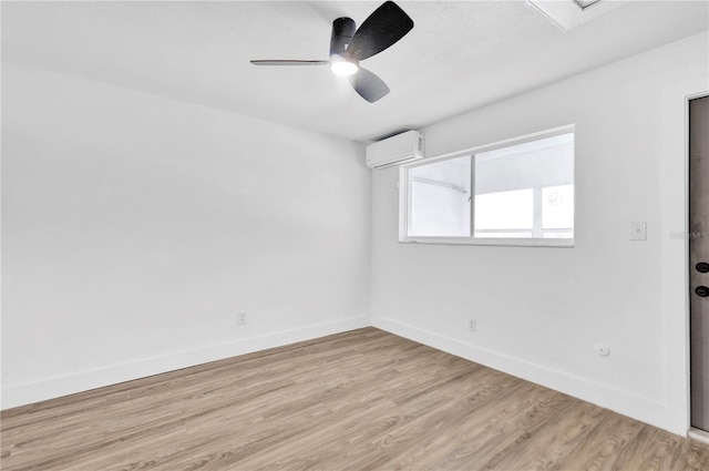 empty room featuring ceiling fan, light wood finished floors, a wall mounted air conditioner, and baseboards