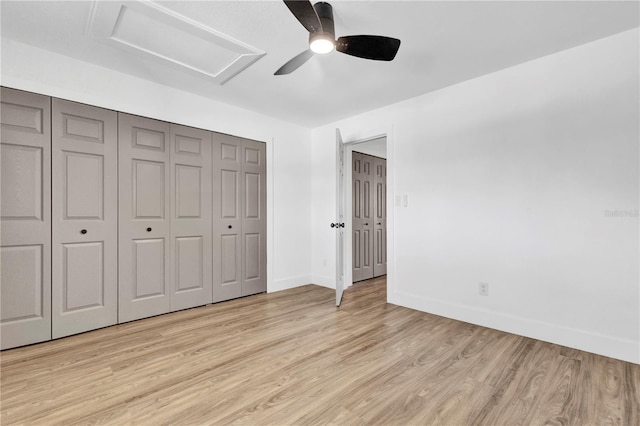 unfurnished bedroom with attic access, a closet, light wood-style flooring, and baseboards