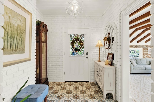 entryway with an inviting chandelier, brick wall, beamed ceiling, and tile patterned floors