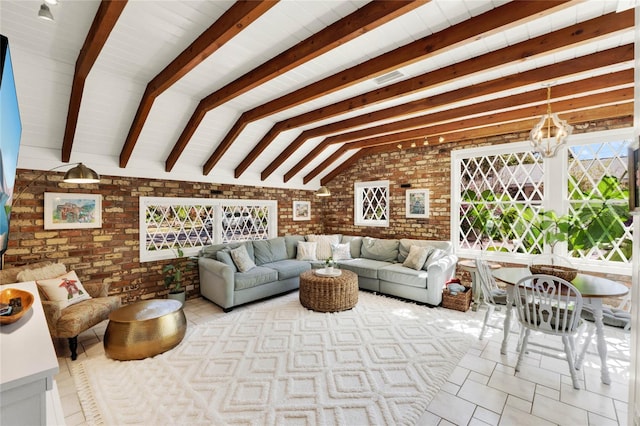 living area with vaulted ceiling with beams, brick wall, and an inviting chandelier