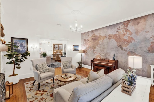 living area with a chandelier, an accent wall, baseboards, and wood finished floors