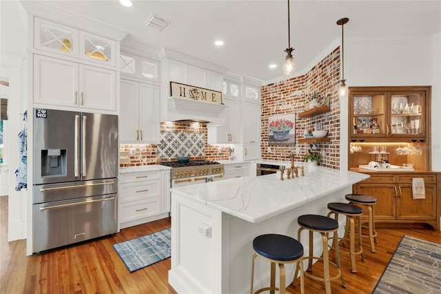 kitchen with stainless steel fridge with ice dispenser, stove, crown molding, light wood-style floors, and premium range hood