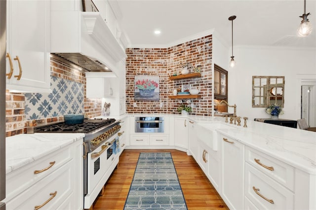 kitchen featuring range with two ovens, crown molding, custom exhaust hood, tasteful backsplash, and a sink