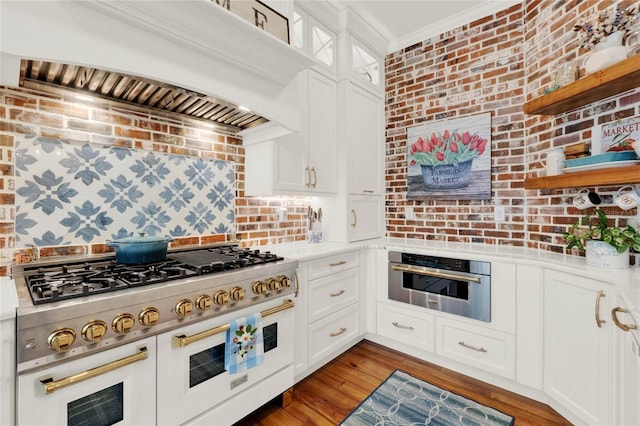 kitchen with range with two ovens, crown molding, custom exhaust hood, brick wall, and oven