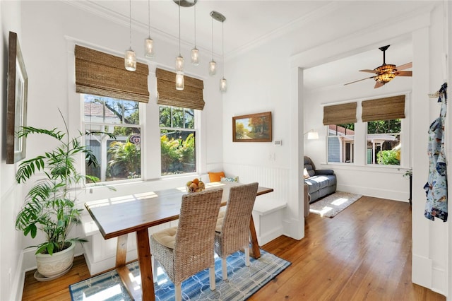 dining room featuring ornamental molding, breakfast area, wood finished floors, and a wealth of natural light