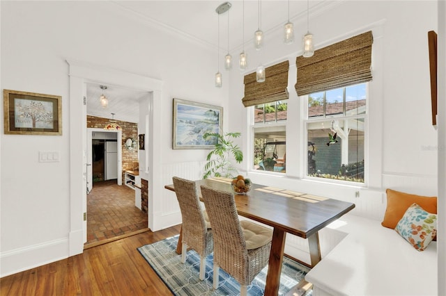 dining space featuring wood finished floors and crown molding