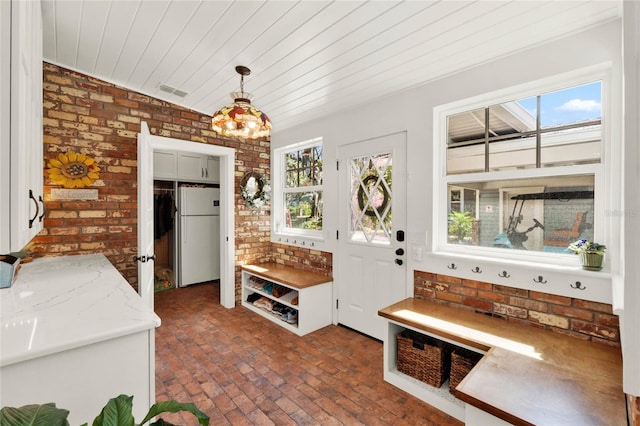 mudroom featuring brick floor, brick wall, visible vents, and plenty of natural light