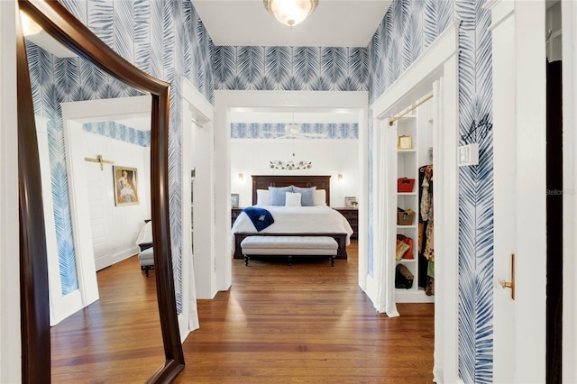 bedroom with wood finished floors, baseboards, and wallpapered walls