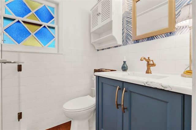 bathroom featuring toilet, vanity, and tile walls