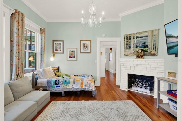 bedroom with a notable chandelier, a fireplace, wood finished floors, baseboards, and ornamental molding