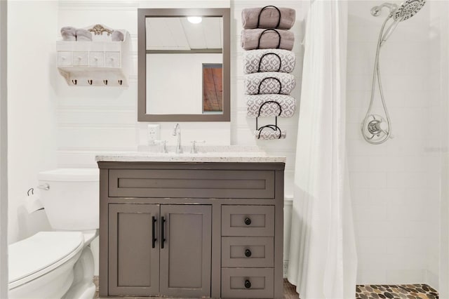 full bathroom with a tile shower, vanity, and toilet