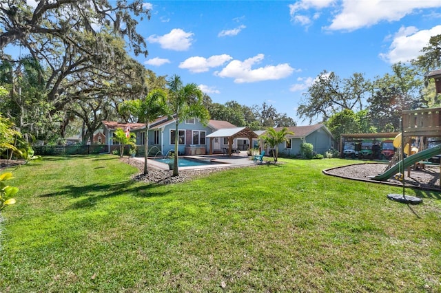 view of yard featuring a playground, a patio area, fence, an outdoor pool, and driveway