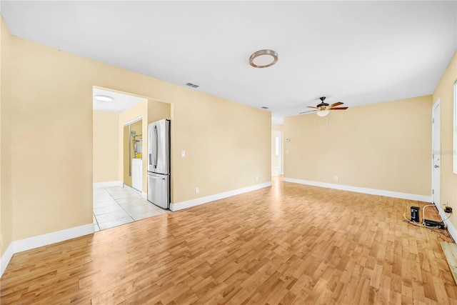 empty room with light wood-style floors, ceiling fan, visible vents, and baseboards