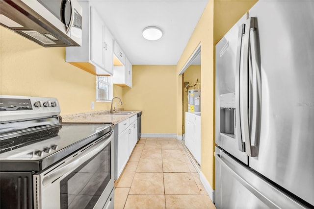 kitchen featuring light stone counters, light tile patterned floors, stainless steel appliances, white cabinets, and a sink