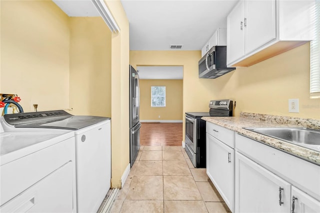 kitchen with stainless steel appliances, washing machine and dryer, light countertops, and white cabinets