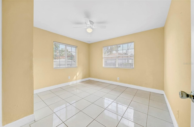 empty room with light tile patterned floors, ceiling fan, and baseboards