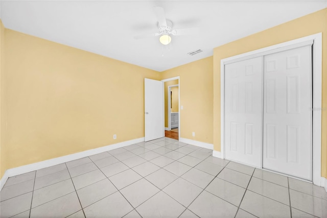 unfurnished bedroom featuring light tile patterned flooring, a ceiling fan, visible vents, baseboards, and a closet