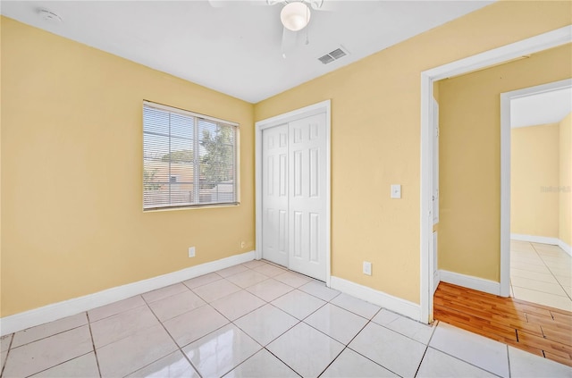 unfurnished bedroom with baseboards, visible vents, a ceiling fan, a closet, and light tile patterned flooring