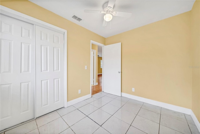 unfurnished bedroom featuring a closet, light tile patterned flooring, visible vents, and baseboards