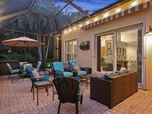 patio terrace at dusk featuring outdoor lounge area and a lanai