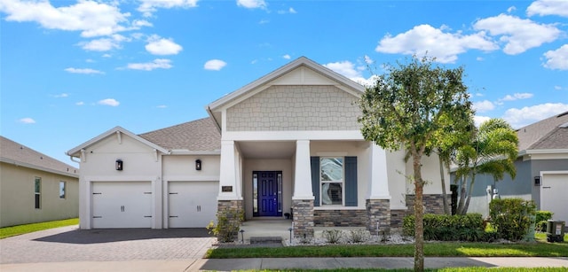 view of front facade featuring stone siding, decorative driveway, an attached garage, and stucco siding