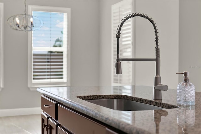 room details with a chandelier, stone counters, a sink, and baseboards