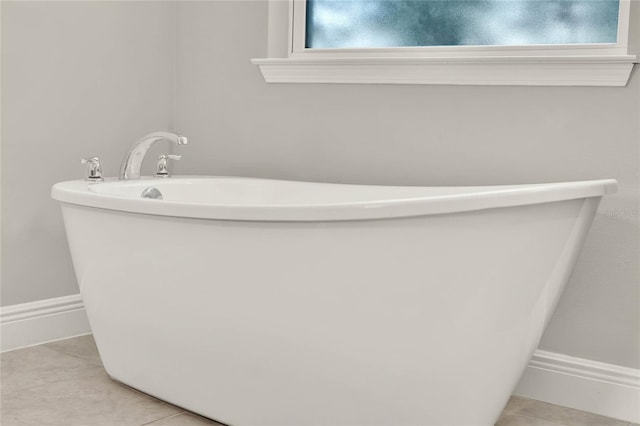 full bath featuring baseboards, a freestanding tub, a wealth of natural light, and tile patterned floors