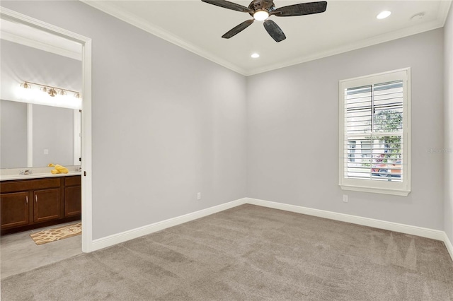 unfurnished bedroom featuring light carpet, ornamental molding, a sink, and baseboards