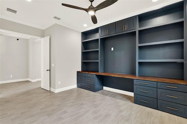 unfurnished office with light wood-style flooring, visible vents, and built in desk