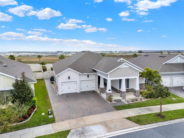 view of front of property featuring decorative driveway, a porch, a gate, fence, and a garage