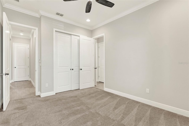 unfurnished bedroom with carpet floors, visible vents, baseboards, ornamental molding, and a closet