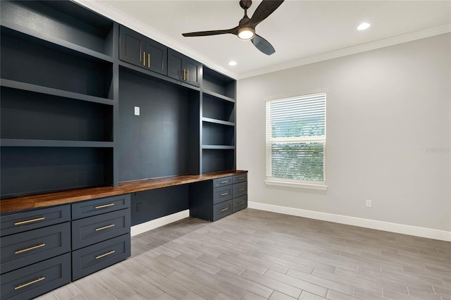 unfurnished office featuring baseboards, a ceiling fan, built in study area, crown molding, and light wood-type flooring