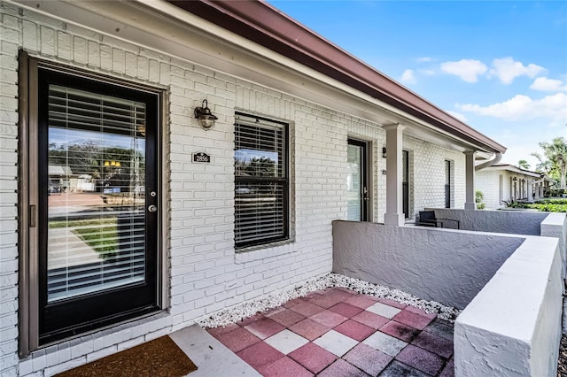 entrance to property with covered porch and brick siding