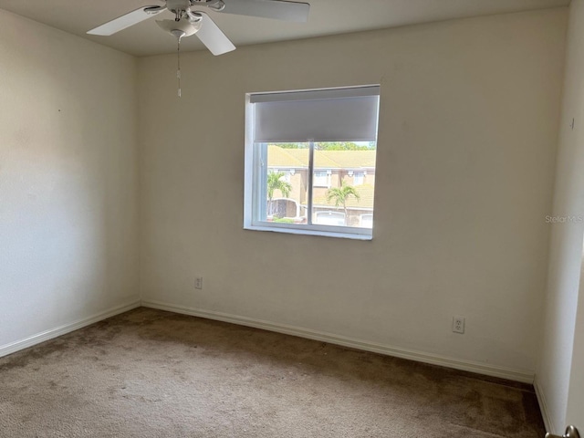 carpeted empty room with a ceiling fan and baseboards