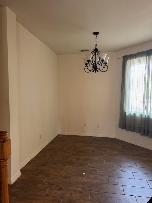 spare room with baseboards, visible vents, dark wood-type flooring, and a notable chandelier