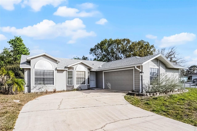 single story home with an attached garage, driveway, a shingled roof, and brick siding