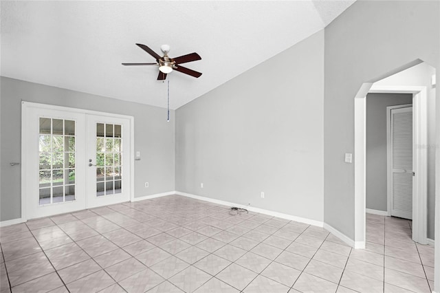 empty room with french doors, light tile patterned floors, a ceiling fan, vaulted ceiling, and baseboards