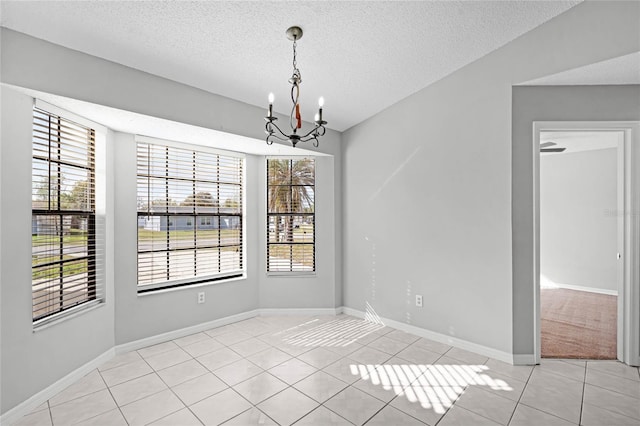 unfurnished dining area with a chandelier, a wealth of natural light, light tile patterned flooring, and a textured ceiling