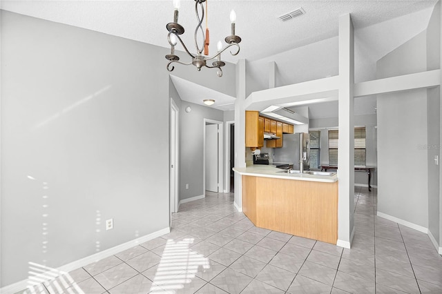 kitchen with lofted ceiling, light tile patterned flooring, baseboards, light countertops, and appliances with stainless steel finishes