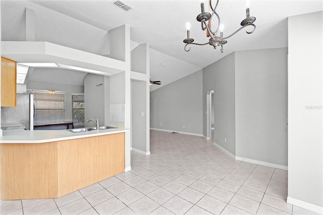 kitchen with light tile patterned floors, visible vents, vaulted ceiling, a sink, and fridge