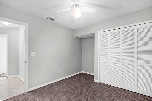 unfurnished bedroom with a textured ceiling, a closet, carpet, and visible vents