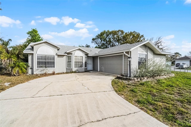 ranch-style home featuring a garage, concrete driveway, brick siding, and a front lawn