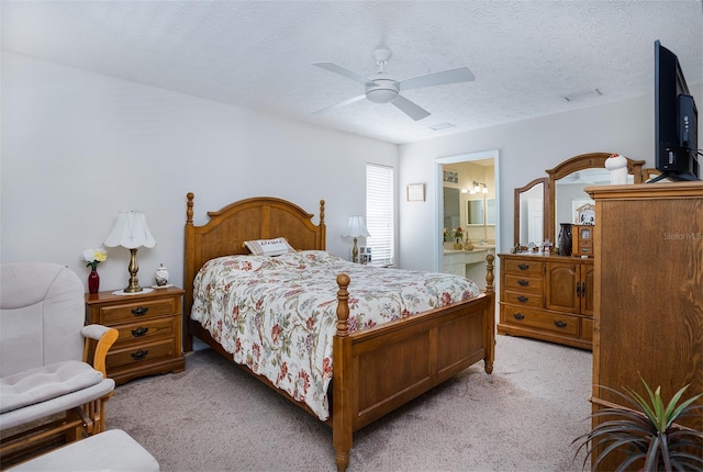 bedroom featuring light carpet, ensuite bath, a ceiling fan, and a textured ceiling