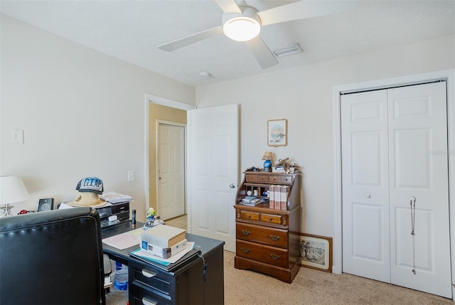 office space with visible vents, a ceiling fan, and light colored carpet